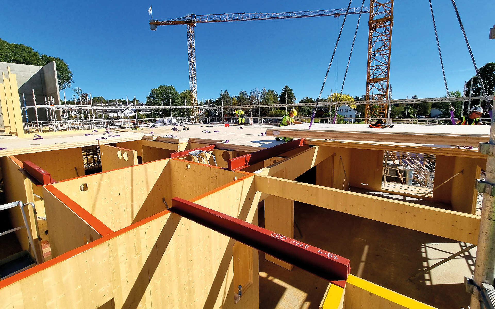 Mass timber construction site with CLT panels installation and workers assembling timber floor structure 