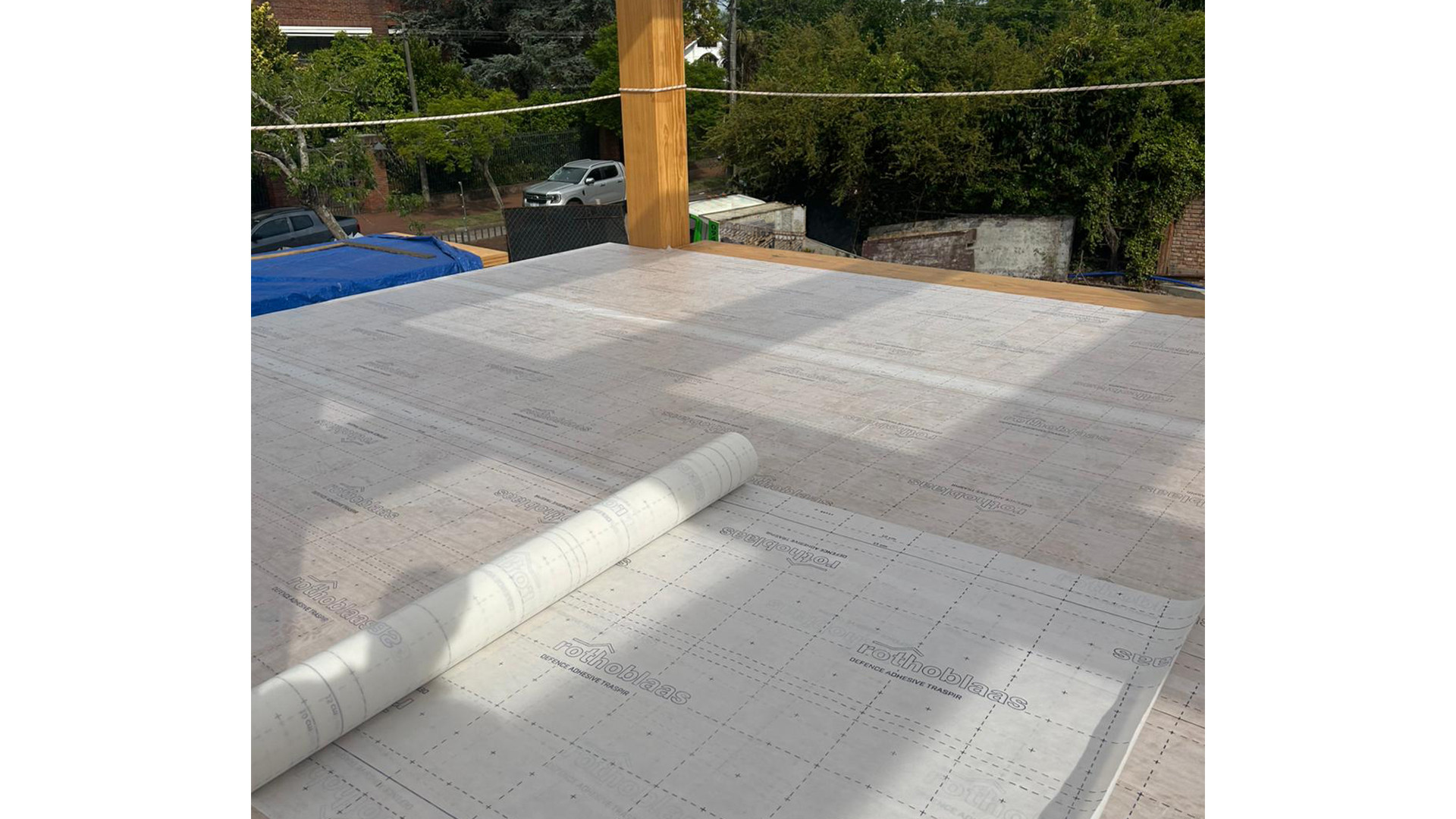CLT floor with self-adhesive breathable membrane partially installed during mass timber construction for timber protection on site.