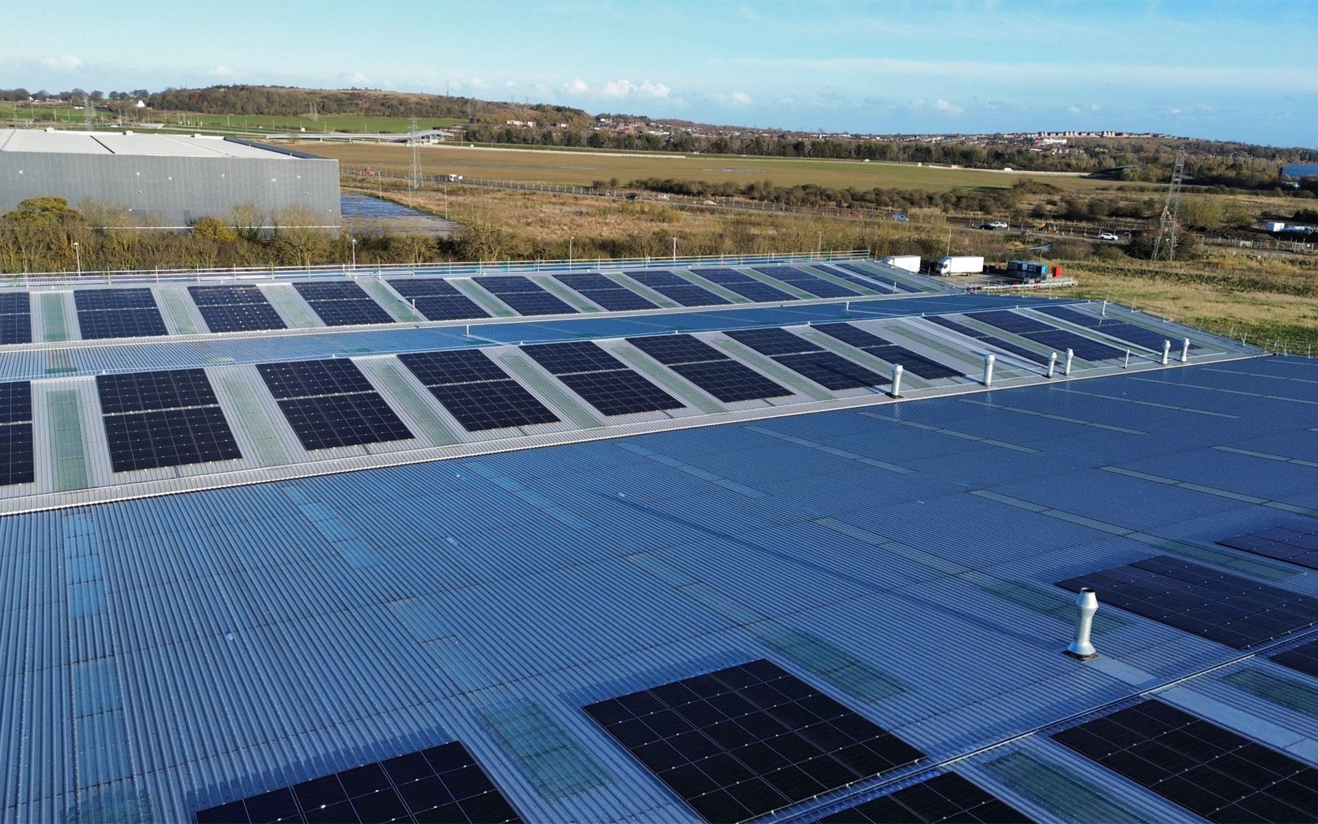 Industrial roof with photovoltaic panels and integrated skylight fall protection system for safe maintenance activities